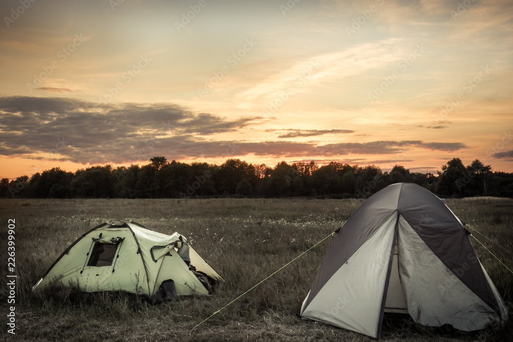 Camping tents on camping sites on summer flatland field plain and dramatic sunset sky during camping holidays