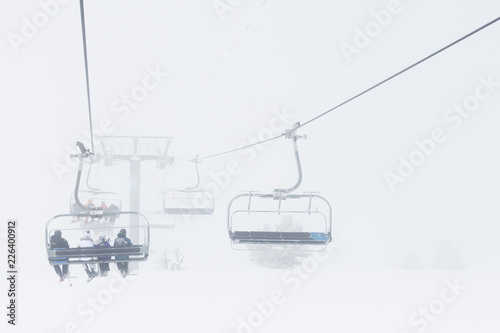 The chair alpine skiing lift in fog. cloudy snow day in mountains.