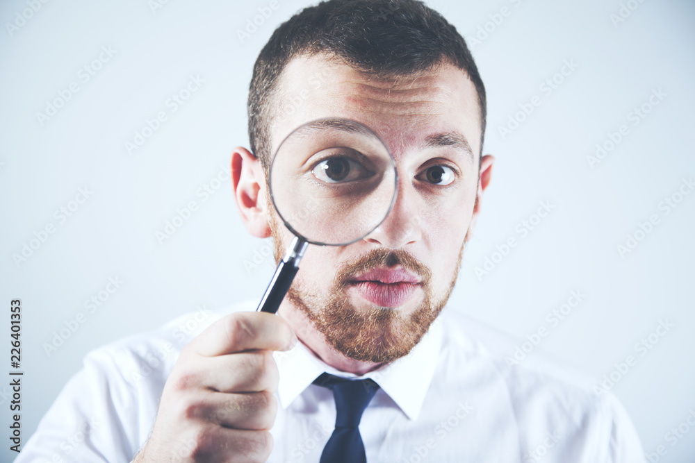 young man looking through a magnifying glass young man looking through a magnifying glass