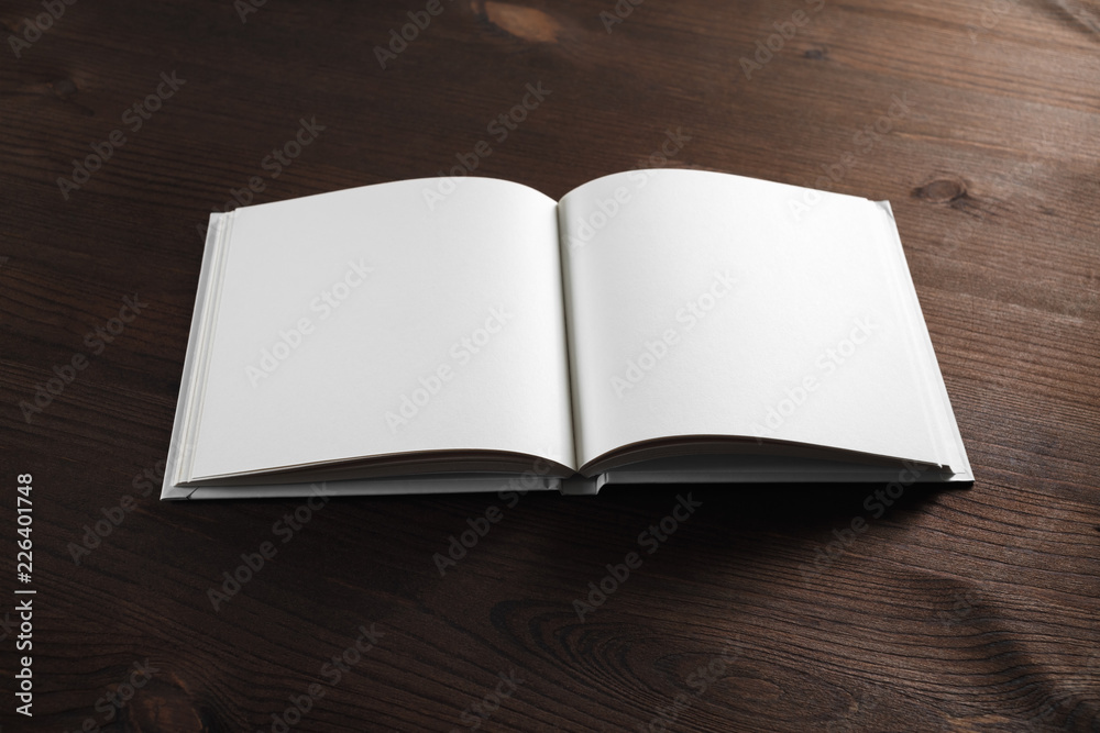 Fototapeta premium Open book or notebook with blank pages on wood table background.