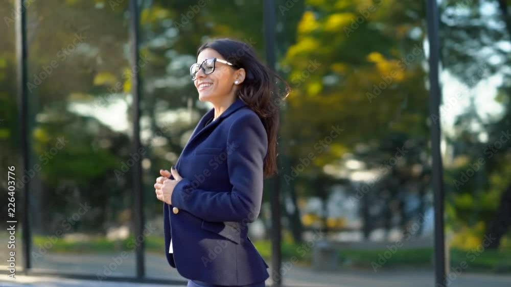 Beautiful businesswoman coming out from office building in excellent mood, she successfully presented the project, won. Success, achievement in business, young specialist concept Beautiful businesswoman coming out from office building in excellent mood, she successfully presented the project, won. Success, achievement in business, young specialist concept