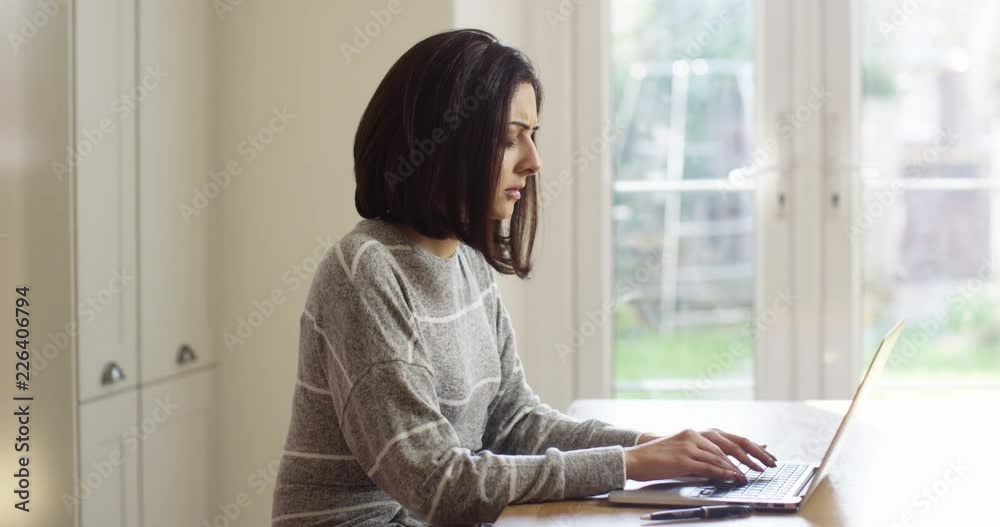 4K Serious Asian woman deep in thought while typing on laptop. Slow motion.