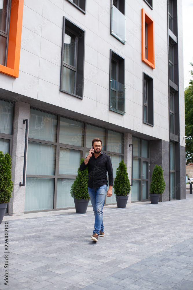 A man with a beard goes and speaks by phone