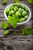 Bowl of cucamelons in plate  on rustic table vertical