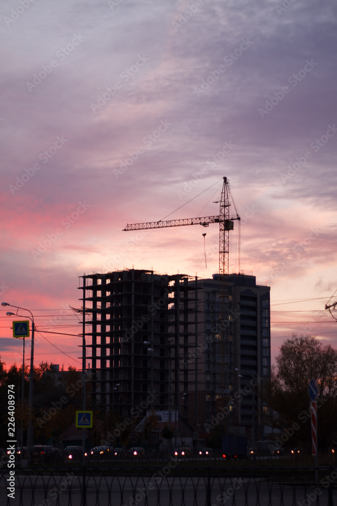 construction building under construction on sunset background autumn construction crane street machine evening beauty purple pink