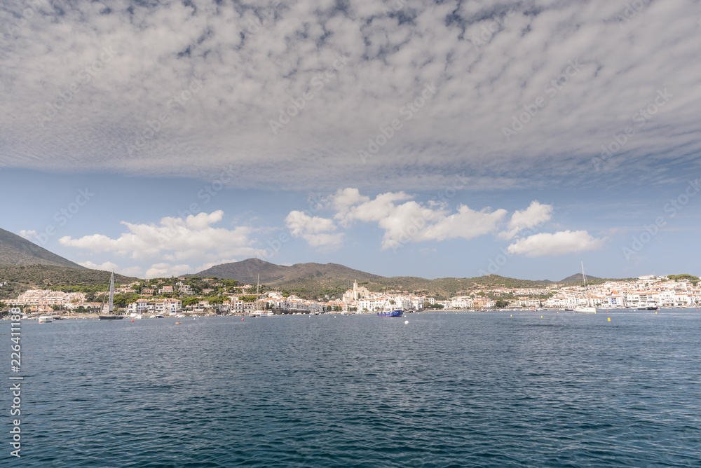 Vista del pueblo de Cadaqués en Alt Empordàn , llegando desde el mar, cielo azul con nubes 