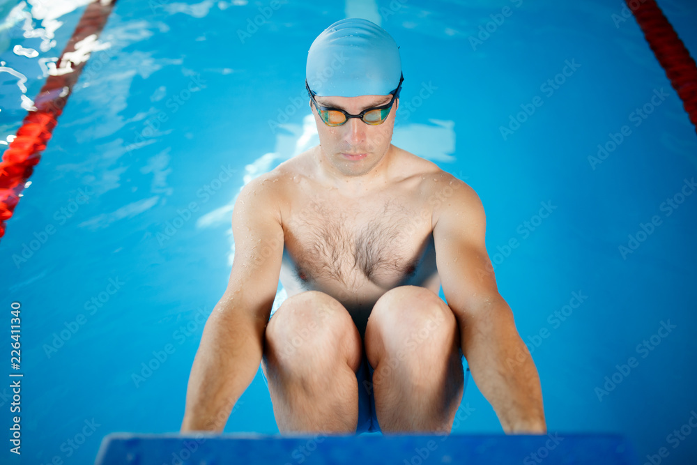 Photo athlete in blue rubber cap and glasses pushing in pool