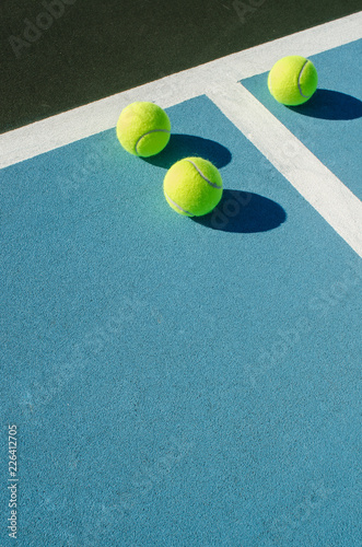 Three tennis balls on blue tennis court © joe