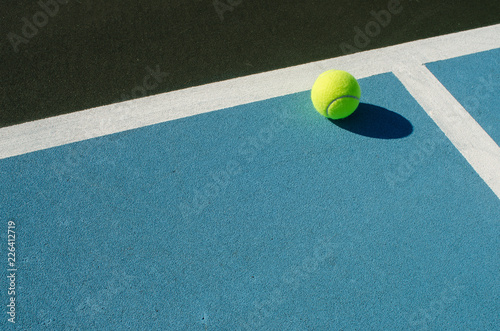 Tennis ball rests on blue tennis court © joe