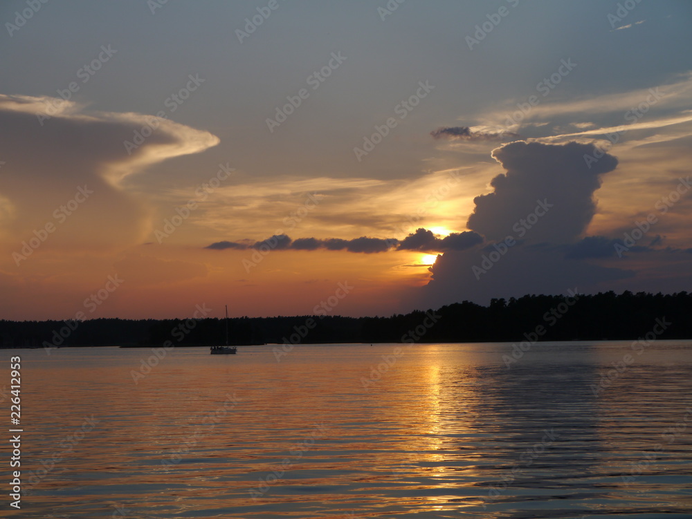 SOnnenuntergang am See mit Boot und Wolken