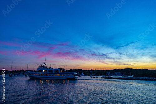Multilevel motor boat with sunrise sunset sky dark reflections water blue vacation recreational passenger travels harbor