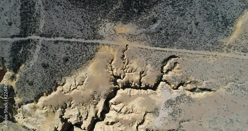 Aerial senital drone scene of Ocre Canyon in Famatina Mountains and Yellow river. Camera ascemds. Detail of canyon's gullies, golden river, cliff and eroded landscape. La rioja, Agentina photo