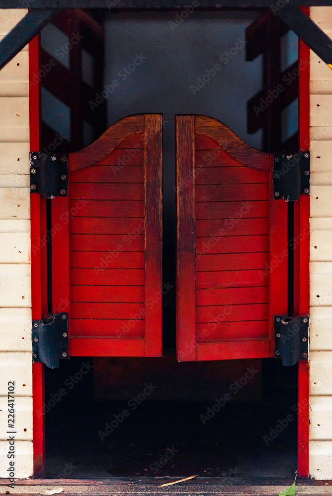 Red closed Western Saloon doors on a white wooden wall on a bright sunny  day Stock-foto | Adobe Stock