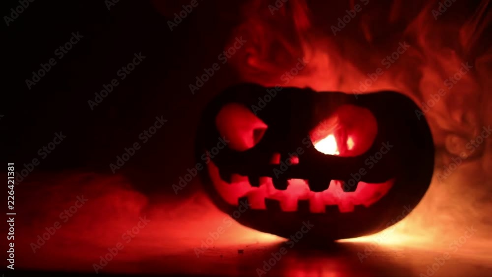 Halloween pumpkin smile and scrary eyes for party night. Close up view of scary Halloween pumpkin with eyes glowing inside at black background. Selective focus