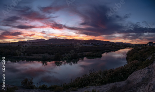 Banner panorama of a dark sunset with clouds reflecting off the river © Boyce