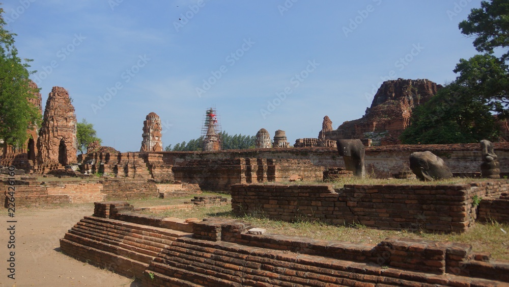 Buddhist temple with ruins, colorful shrines & a famed Buddha head surrounded by tree roots - Wat Phra Mahatat Buddhist temple with ruins, colorful shrines & a famed Buddha head surrounded by tree roots - Wat Phra Mahatat