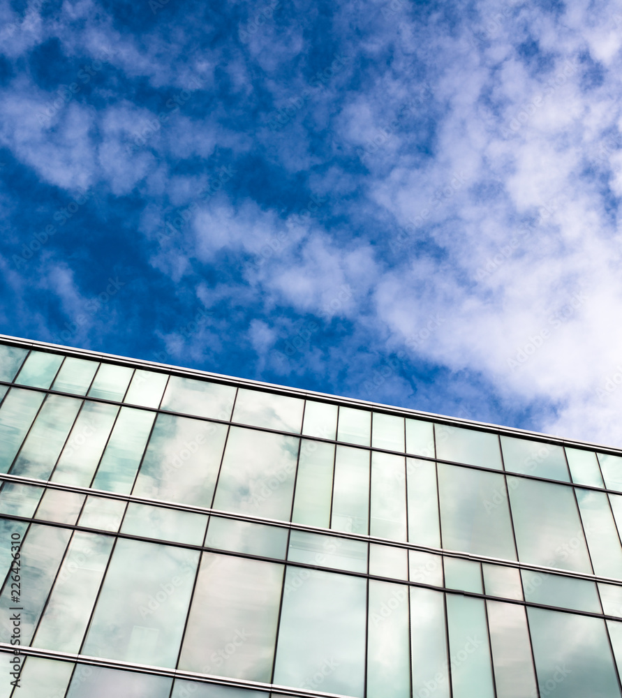 blue sky and clouds reflected in windows of modern building blue sky and clouds reflected in windows of modern building