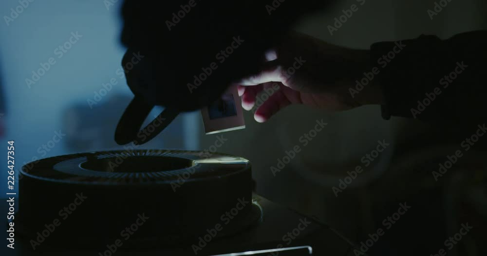 Man operating analog slides projector in a dark misty room