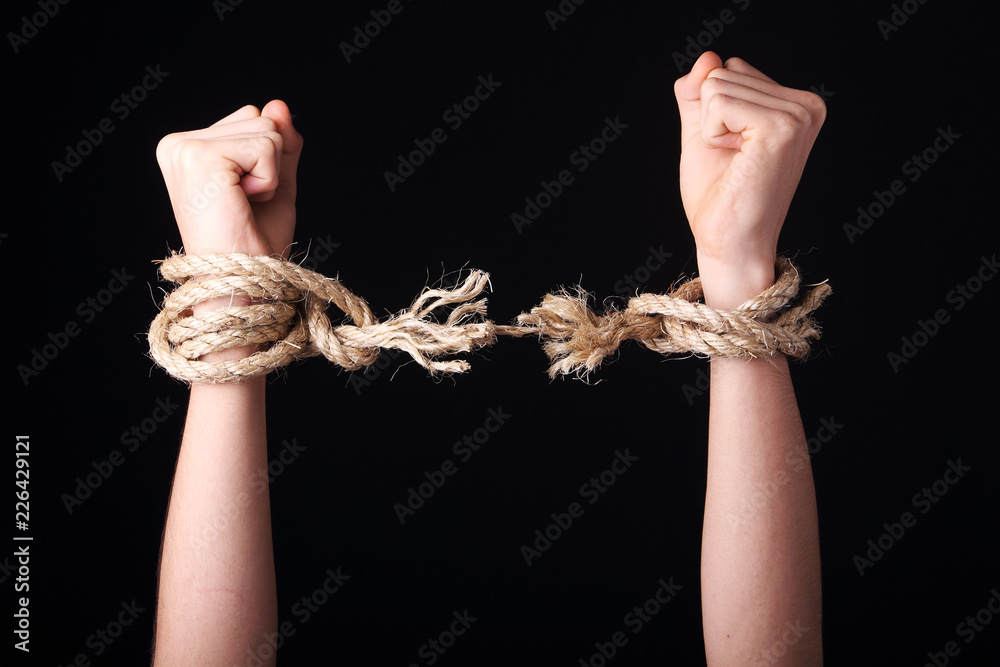 Unrecognizable person getting free is raising arms showing a frayed rope