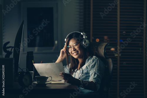 Portrait of Asian Businesswoman sitting and working hard with happiness action on the table with front of computer desktop in workplace at late time, Work hard and too late concept
