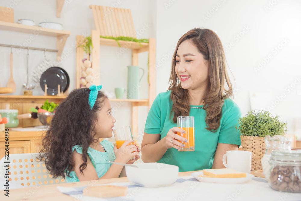 Beautiful asian mother and daughter having breakfast together at home in the morning