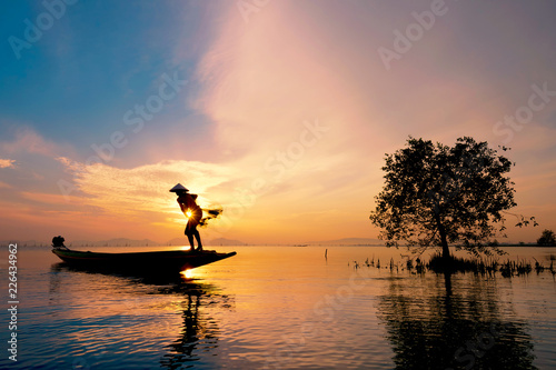 Fisherman on boat catching fish with sunrise