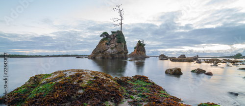 Pacific ocean coast at evening, overlooking Tillamook Bay, Oregon. Rock formations stick out of the still water. photo
