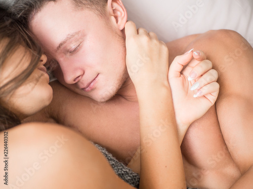 High angle view of beautiful happy young couple hugging while sleeping on bed.