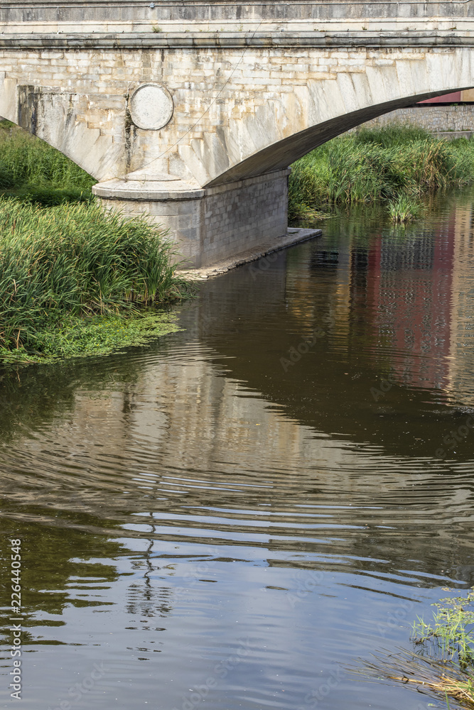 Water reflection on an old heritage stone bridge in Girona, Catalonia