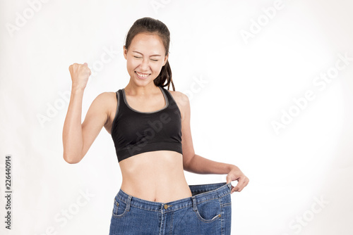 Happy pretty woman lost weight to slim shape with big jeans on white background.