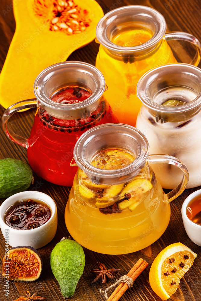 Vertical iimage of glass teapots set with colorful natural hot tea decorated with frruits and jam at wooden dark board background. Vertical iimage of glass teapots set with colorful natural hot tea decorated with frruits and jam at wooden dark board background.