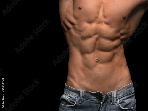 Muscular male torso isolated on black background.