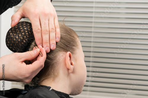 Canvas Print hairdresser inserts a hairpin under the hairnet