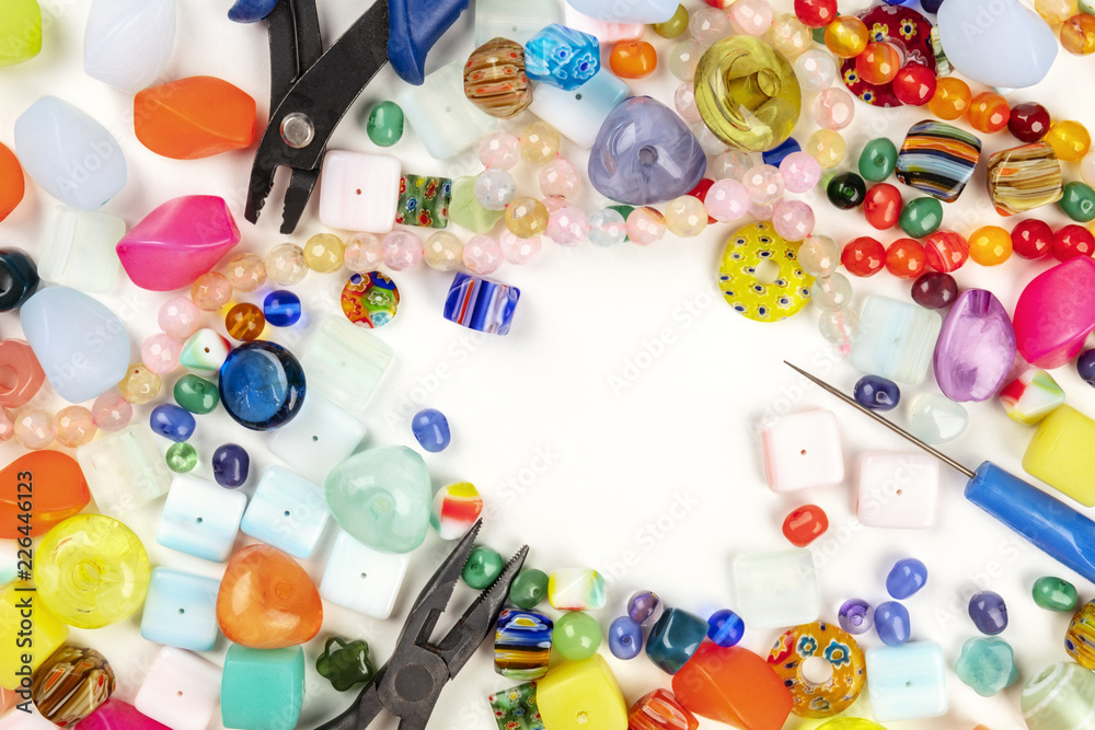 Fototapeta premium An overhead photo of many different beads with tools for making jewellery, on a white background with a place for text