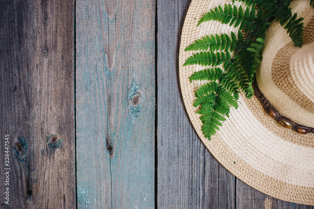 a hat, a fern leaf on the wooden background, copy space