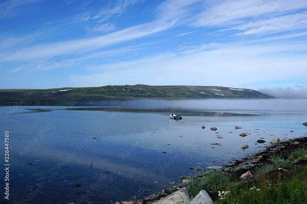 A boat in the north bay in summer morning with reflection of sky on water surface. A boat in the north bay in summer morning with reflection of sky on water surface.