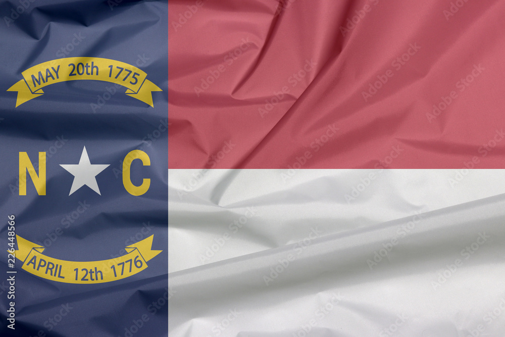 Fototapeta premium Fabric flag of North Carolina. Crease of North Carolina flag background, A blue union, a white star with N and C, the circle containing the same to be one-third.