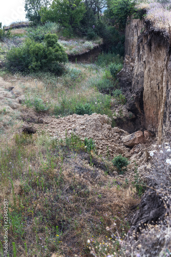 Mountain landslide disaster in sesmically dangerous area. Large cracks in earth  descent of large layers of earth blocking road. Mortal danger of damming people at foot of landslide slopes of mountain