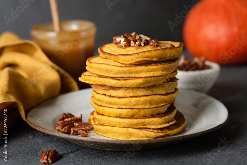 Pumpkin pancakes with pecan nuts and salted caramel sauce on a plate. Healthy tasty autumn comfort food