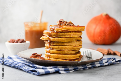 Stack of pumpkin pancakes with caramel sauce and pecan nuts on a plate, closeup view. Tasty autumn comfort food
