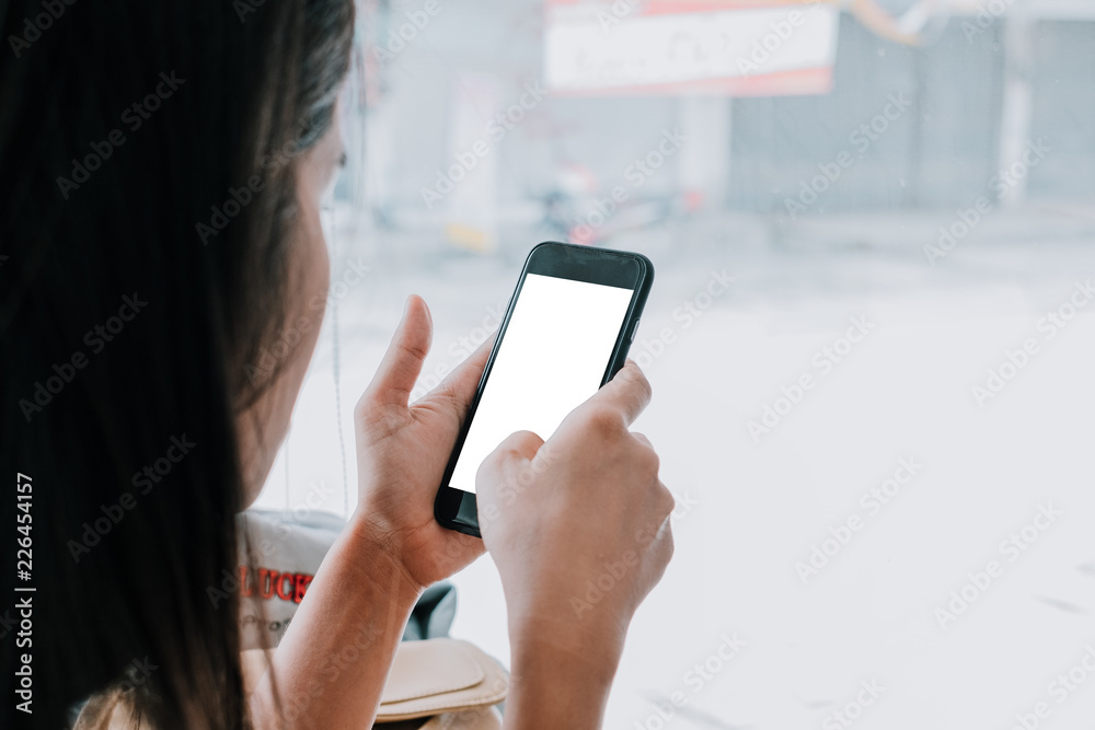 Woman relaxing while using smartphone blank screen for graphics display montage. Over the shoulder view of