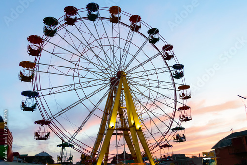 Amusement park on the background of the sunset. Ferris wheel