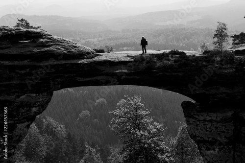 Man standing on the top of the rock hill in the Czech mountains at Pravčická brána in Hřensko