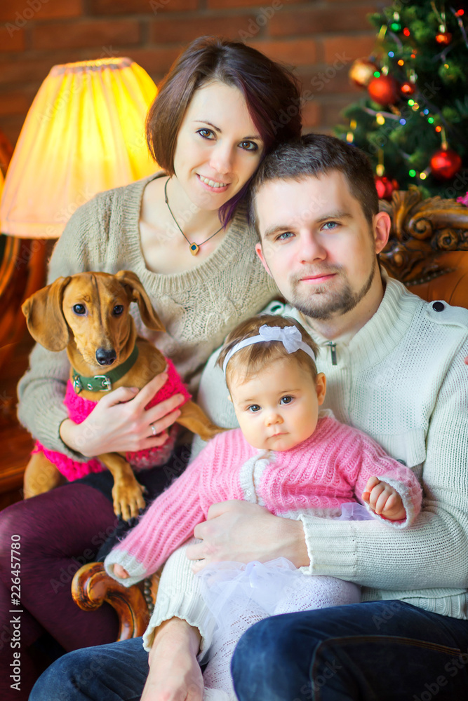 happy family with dog sits and hugs near the festive Christmas tree