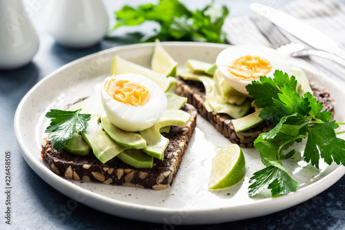 Toast with avocado and boiled egg on a plate, closeup view. Healthy breakfast, healthy eating or snack concept