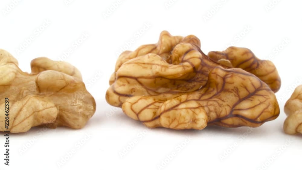 Row of walnuts without the shell are moving horizontally from one side of the frame to other. Isolated on the white background. Close-up. Macro. Row of walnuts without the shell are moving horizontally from one side of the frame to other. Isolated on the white background. Close-up. Macro.