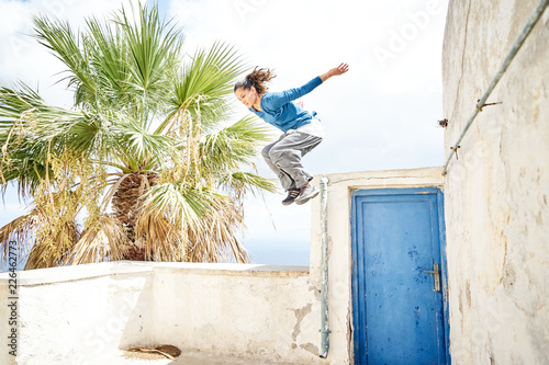 Frau macht einen Parkour Sprung in einem Dorf in Santorin 