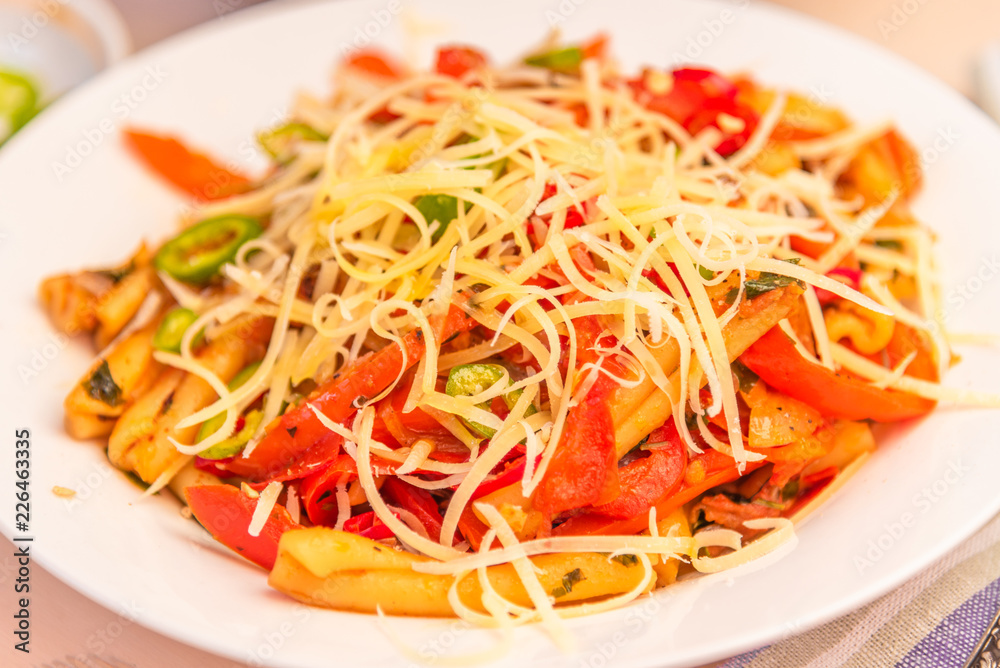 Italian food - Pasta with red pepper and parmesan on a white plate close-up Italian food - Pasta with red pepper and parmesan on a white plate close-up