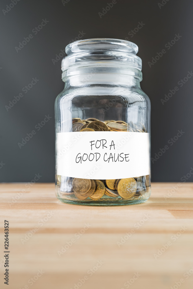 Jar with golden coins on natural wooden background. Money saving for a good cause abstract concept. Jar with golden coins on natural wooden background. Money saving for a good cause abstract concept.