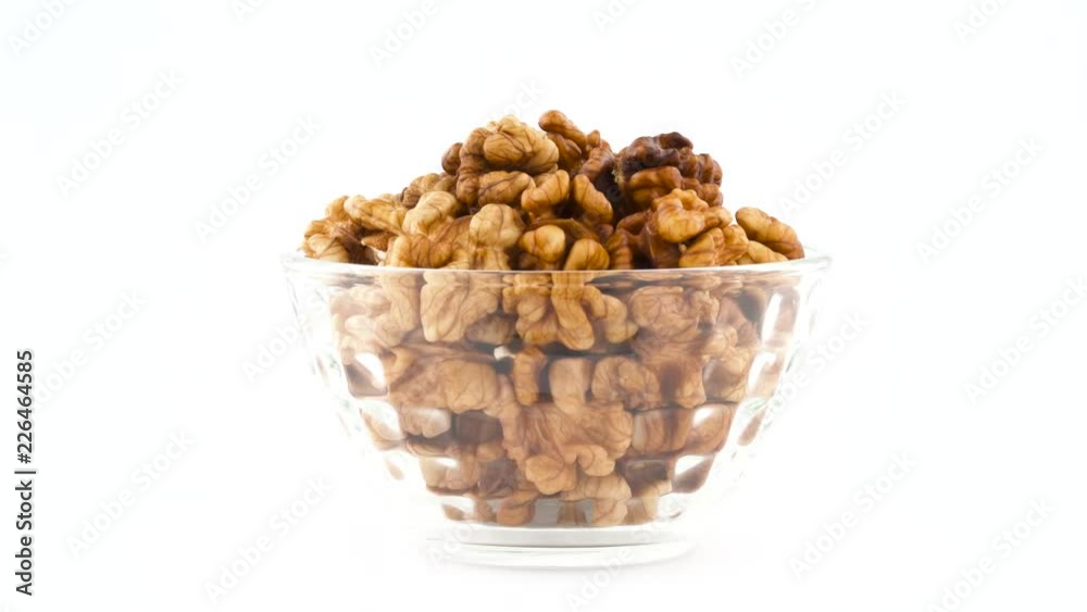 Heap of walnuts in glass bowl. Rotating on the turntable isolated on the white background. Close up. Macro. Heap of walnuts in glass bowl. Rotating on the turntable isolated on the white background. Close up. Macro.